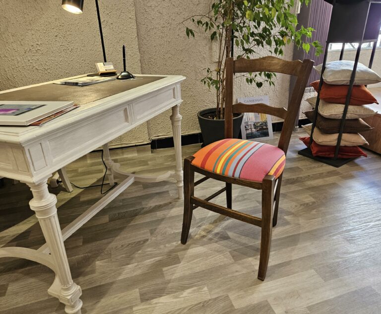 Chaise paillée transformée en assise bultex, recouverte d'un tissu rayé dans les couleurs orangées.